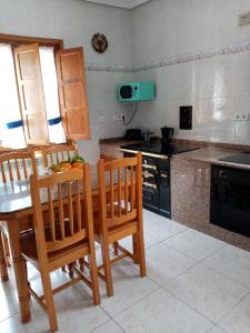 cocina con sillas de madera, mesa y fogones en Casa Nieves en Villaviciosa