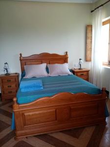 Un dormitorio con una gran cama de madera con sábanas azules en Casa Nieves, en Villaviciosa