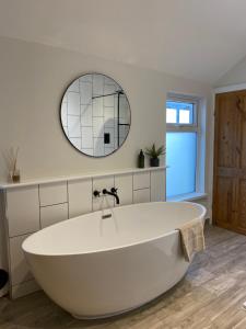 a white bath tub in a bathroom with a mirror at TAFFS MEAD HOUSE Central City Location, nr Stadium, Family Friendly in Cardiff
