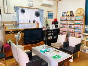 uma sala de estar com uma televisão e uma mesa e cadeiras em Ishigakijima no Sudomari Orihimeno Yado - Vacation STAY 68049v em Ishigaki Island