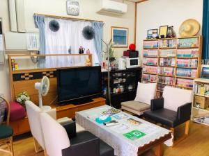 un salon avec une télévision, une table et des chaises dans l'établissement Ishigakijima no Sudomari Orihimeno Yado - Vacation STAY 72074v, à Ishigaki