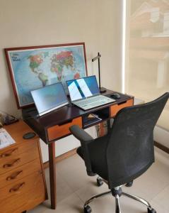 einen Schreibtisch mit einem Computer, einem Laptop und einem Monitor in der Unterkunft Lovely 2B-2B Condo in the best area of Cuenca. in Cuenca