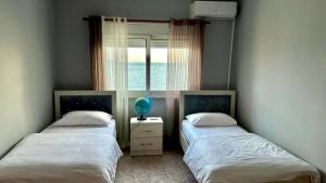 two twin beds in a room with a window at Sea View Apartaments in Durrës