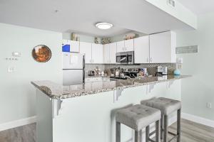 a kitchen with white cabinets and two bar stools at Beach Front 16th Flr, Best Ocean View, New Upgrades in Destin