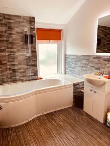 La salle de bains est pourvue d'une baignoire blanche et d'un lavabo. dans l'établissement Luxury 2 bed apt 4 mins from M6 J44 pet friendly,, à Carlisle