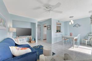 a living room with a blue couch and a dining room at Coastal Cheer in Bradenton Beach