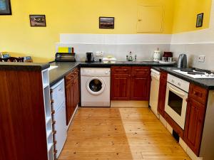 a kitchen with a washing machine and a wooden floor at Bloomfield Steading in Laurencekirk