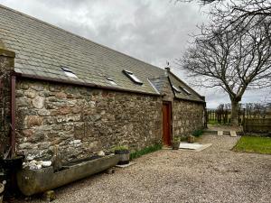 an old stone building with a red door at Bloomfield Steading in Laurencekirk