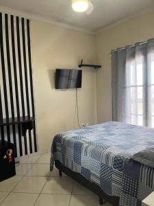 um quarto com uma cama e uma televisão de ecrã plano em POUSADA ONDA CARIOCA em Cabo Frio