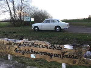 a white car parked in a field next to a sign at Kranich-Holzferienhaus 'Kleine Auszeit' in Rehden