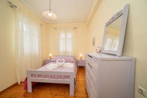 a bedroom with a bed with a dresser and a tv at House of Hapiness in Assos in Asos