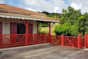 une clôture rouge sur une maison avec une terrasse en bois dans l'établissement Idéal groupe : Villa 150m2 + piscine + vue mer, à La Trinité
