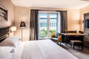 Cette chambre comprend un lit, un bureau et une fenêtre. dans l'établissement Sheraton Duesseldorf Airport Hotel, à Düsseldorf