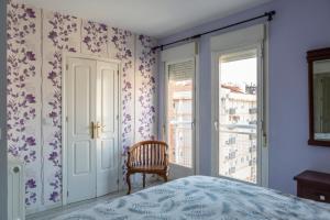 een slaapkamer met een bed, een stoel en een raam bij Duplex Luz in Jaén