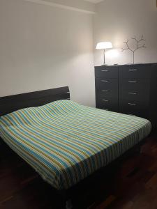 ein Bett mit gestreifter Decke und eine Kommode in einem Schlafzimmer in der Unterkunft RG HOUSE in Trani