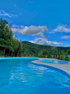 a pool with blue water and mountains in the background at Saliuk Lodge in Solochyn