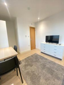a living room with a desk and a tv and a piano at Cozy En-suite near Stratford in London