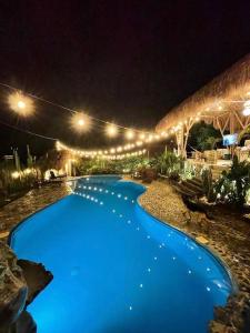 a large blue swimming pool at night with lights at finca playa seca in Santa Fe de Antioquia
