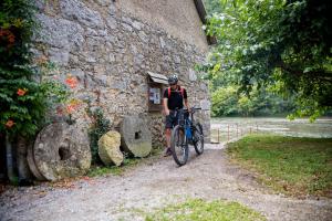 un hombre montando una bicicleta al lado de un edificio de piedra en Madronič family estate - Kolpa river en Stari Trg ob Kolpi