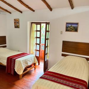 a bedroom with two beds and a door to another room at Posada Del Valle Lodge in Urubamba