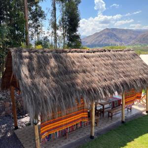 a hut with benches and a thatched roof at Posada Del Valle Lodge in Urubamba