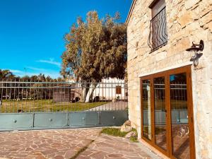 a building with a glass door and a fence at Casa di Pietra in San Giovanni Suèrgiu