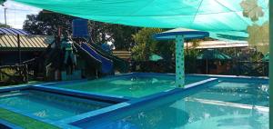 a swimming pool with a blue umbrella and a swimming at Villa Lenda Resort - San Manuel, Pangasinan 