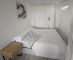 un letto bianco in una camera con tavolo in legno di Appartement à Hendaye avec piscine et à côté de la plage a Hendaye