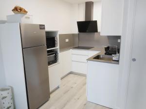 cocina con armarios blancos y nevera de acero inoxidable en Appartement à Hendaye avec piscine et à côté de la plage, en Hendaya