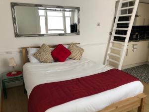 1 dormitorio con 1 cama con manta roja y escalera en Westbourne Terrace en Londres