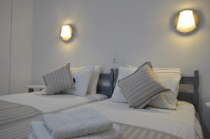 a bedroom with two beds with white sheets and pillows at Pansion L'isola in Skiathos