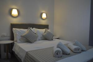 una camera da letto con letto, lenzuola e cuscini bianchi di Pansion L'isola a Città di Skiathos