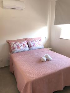 a bedroom with a pink bed with two towels on it at Conforto e Aconchego em Imbassaí/BA in Imbassai