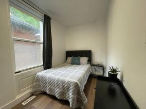 a bedroom with a bed with a comforter and a window at Charming Century Apartments, Steps to downtown in London