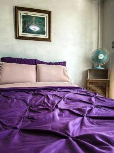 a bed with a purple comforter in a bedroom at Departamento a 25 min del AIFA in Ecatepec
