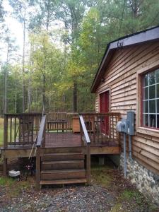una gran terraza de madera frente a una cabaña en Rustic Quaint Cabin In the woods--Pets welcomed, en Dunnsville