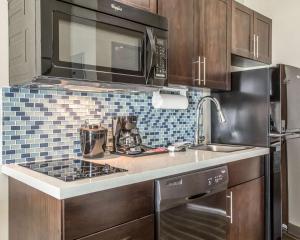 una cocina con electrodomésticos de acero inoxidable y armarios marrones en MainStay Suites Midland, en Midland