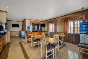 a dining room with tables and chairs and a kitchen at SureStay Hotel by Best Western Falfurrias in Falfurrias