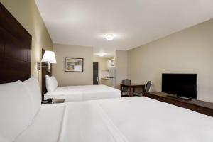 a hotel room with two beds and a flat screen tv at Suburban Studios Denver Central-Arvada in Arvada