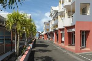 une rue vide avec des palmiers et des bâtiments dans l'établissement Martinique La Trinité KAZAKASSY Studio plain-pied, fonctionnel et vue mer, à La Trinité