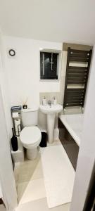 a bathroom with a toilet and a sink and a tub at Cosy flat - with excellent transport links in South Norwood