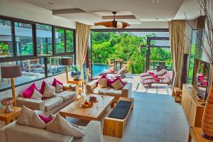 Fully Serviced Grand Villa Luxury Time Phuket في شاطئ بانغ تاو: غرفة معيشة مليئة بالاثاث ونافذة كبيرة
