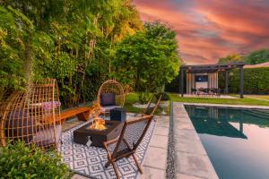 a backyard with a pool and chairs and a table at Fascinating Luxe Two-Level Villa BY THE GLAMHOMES in Biscayne Park