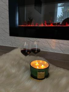 two glasses of wine and a candle in front of a fireplace at La Vista in Stari Banovci