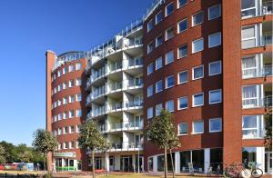 um edifício de tijolos vermelhos com árvores em frente em Haus Nordseebrandung NC24 em Cuxhaven