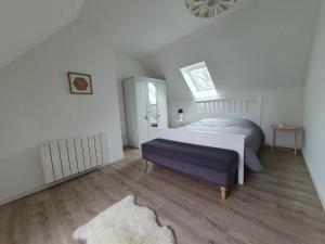 een slaapkamer met een wit bed en een paarse bank bij Le Vaugerin in Bléré