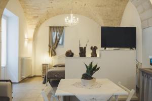 a living room with a bed and a table and a tv at Cà dei Palazzo - Guest House in Martina Franca