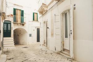 an alley with white buildings and a green door at Cà dei Palazzo - Guest House in Martina Franca