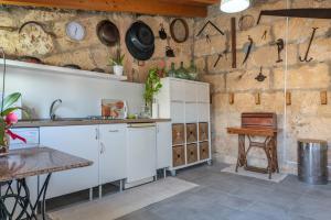 cocina con armarios blancos y pared de piedra en Ca na Mariona in Pollença, en Pollensa