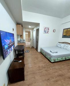 a room with a bed and a table and a flat screen tv at ANIA CONDO STAY in Mactan